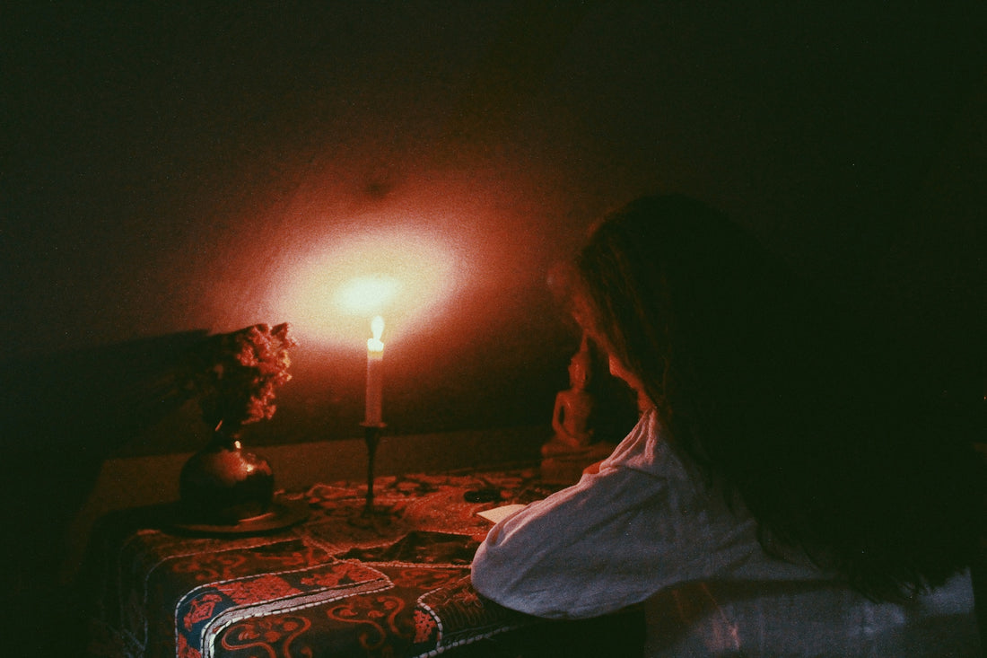 a woman sitting at a table with a candle in the background