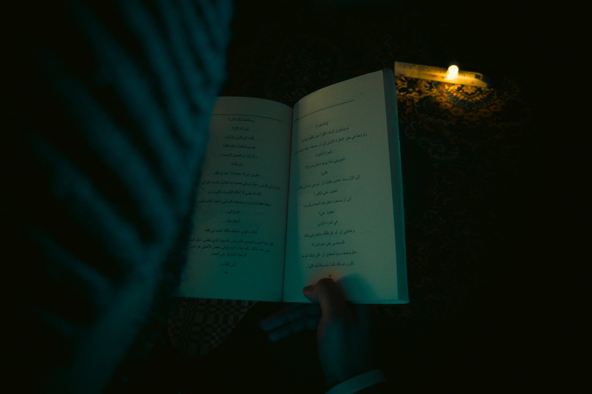 Person reading an open book by candlelight